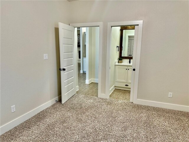 unfurnished bedroom featuring light colored carpet, sink, and ensuite bath