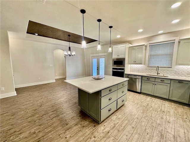 kitchen featuring sink, hanging light fixtures, stainless steel appliances, backsplash, and a kitchen island