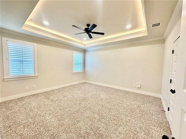 carpeted spare room featuring a tray ceiling, ceiling fan, and ornamental molding