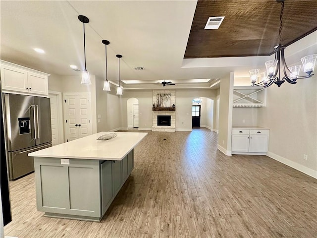 kitchen featuring white cabinets, ceiling fan with notable chandelier, a fireplace, high end fridge, and wood ceiling