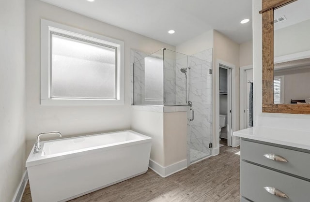 full bathroom with wood-type flooring, vanity, shower with separate bathtub, and toilet