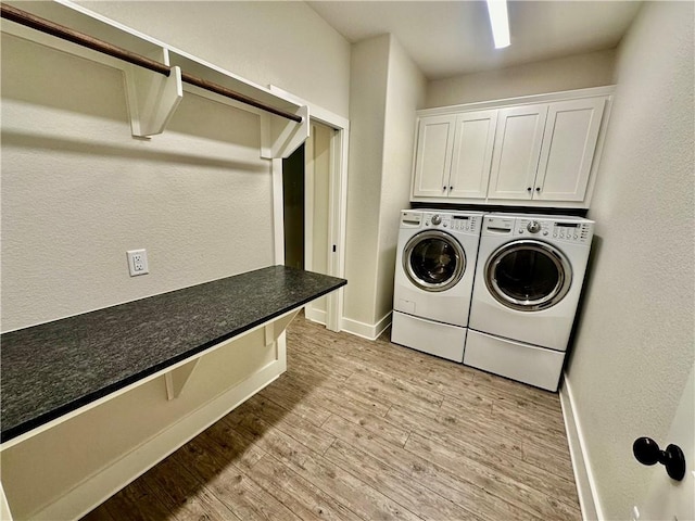 laundry room with light wood-type flooring, washing machine and dryer, and cabinets