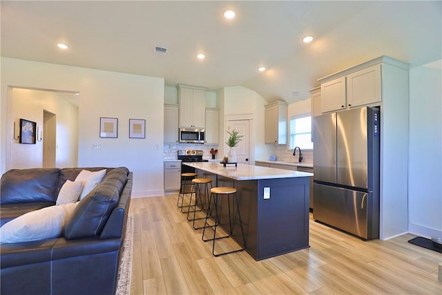 172 Pleasant Path, Somerville, TX 77879 - kitchen featuring stainless steel appliances, a breakfast bar area, open floor plan, light countertops, and light wood finished floors