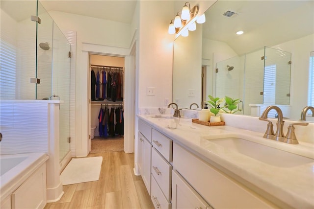 172 Pleasant Path, Somerville, TX 77879 - bathroom with a stall shower, double vanity, wood finished floors, a bath, and a spacious closet