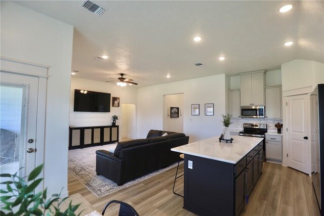 172 Pleasant Path, Somerville, TX 77879 - kitchen with stainless steel appliances, a kitchen breakfast bar, light wood-type flooring, light countertops, and a kitchen island