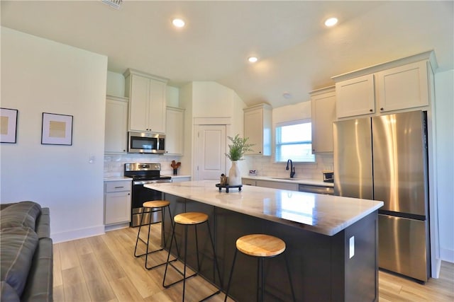 172 Pleasant Path, Somerville, TX 77879 - kitchen featuring stainless steel appliances, a kitchen bar, light wood-style floors, tasteful backsplash, and a center island