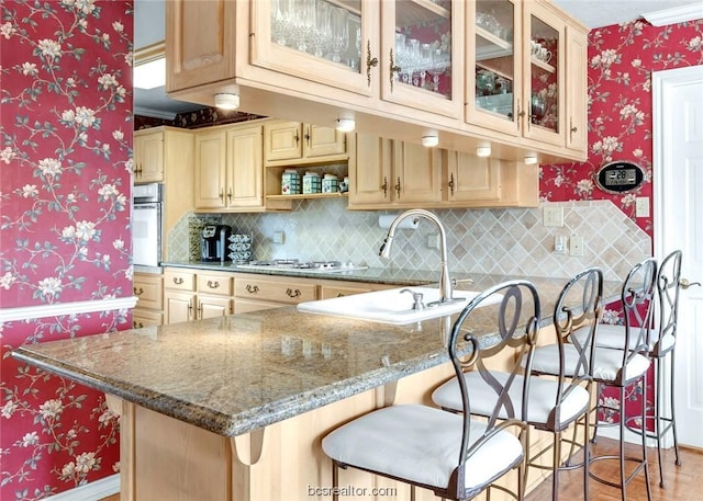 kitchen featuring a breakfast bar area, kitchen peninsula, and stone counters