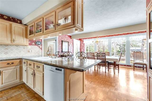 kitchen with kitchen peninsula, white dishwasher, light parquet floors, and sink