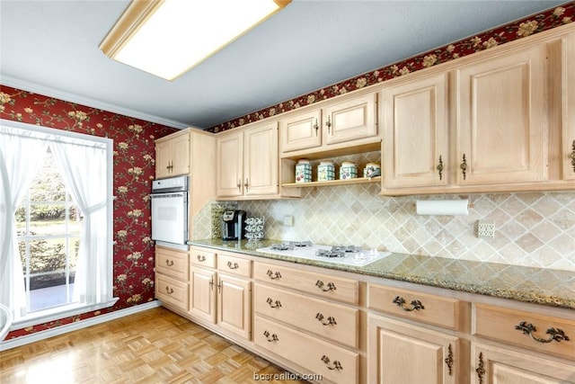 kitchen featuring light brown cabinets, light stone counters, backsplash, light parquet floors, and white appliances