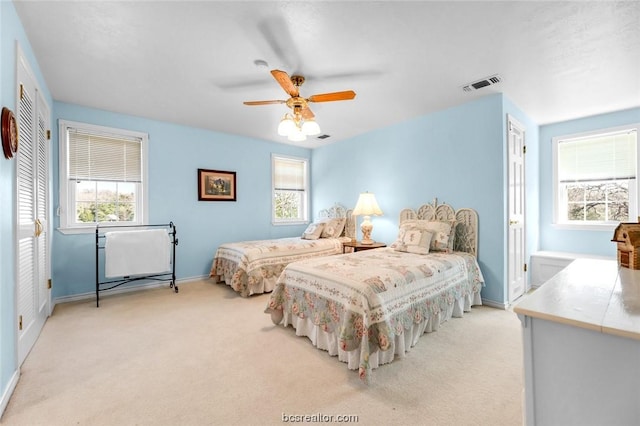 carpeted bedroom with ceiling fan and multiple windows