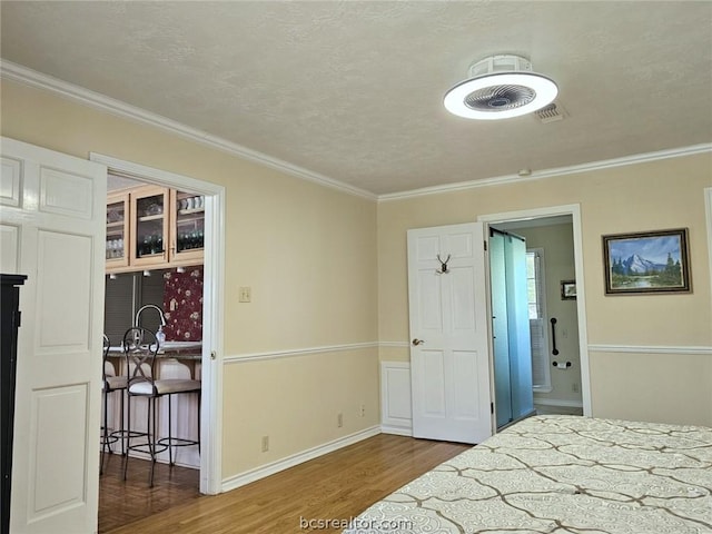 bedroom with hardwood / wood-style floors, ornamental molding, and a textured ceiling