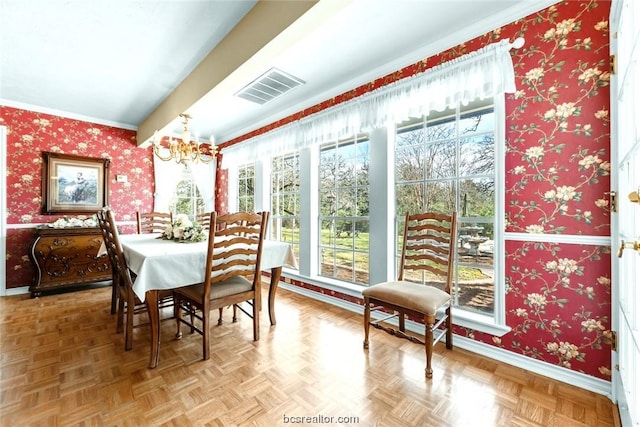 dining room with parquet floors, crown molding, a wealth of natural light, and a notable chandelier