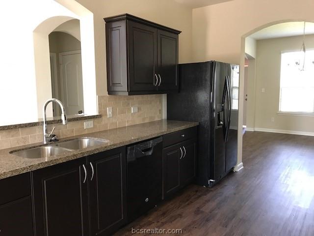 kitchen featuring backsplash, light stone counters, sink, black appliances, and dark hardwood / wood-style floors