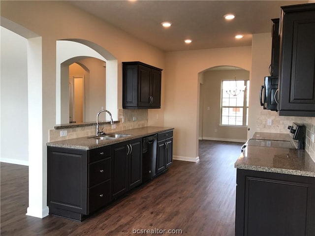 kitchen with tasteful backsplash, sink, black appliances, an inviting chandelier, and dark hardwood / wood-style floors