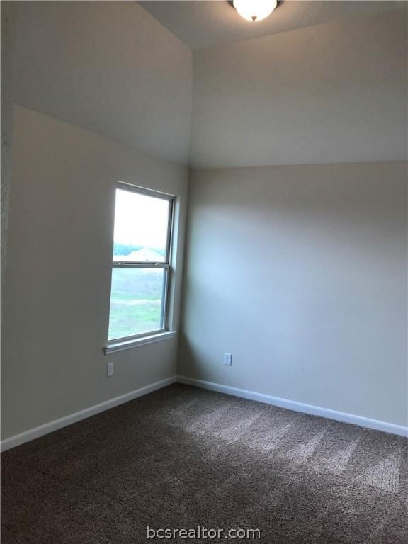 carpeted spare room featuring vaulted ceiling