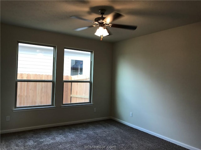 spare room featuring dark colored carpet and ceiling fan