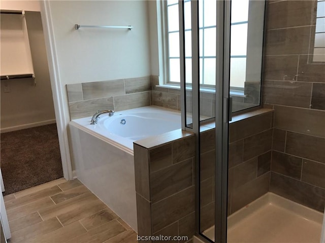 bathroom with hardwood / wood-style flooring and separate shower and tub