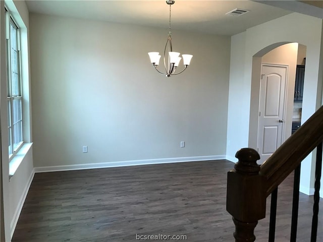 empty room featuring dark wood-type flooring and a notable chandelier