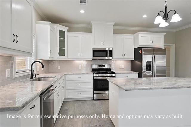 kitchen featuring visible vents, a sink, stainless steel appliances, white cabinetry, and crown molding