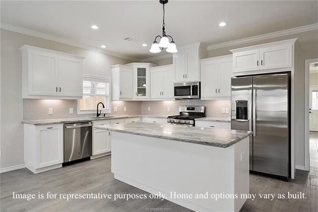 kitchen with a sink, stainless steel appliances, white cabinetry, crown molding, and a center island