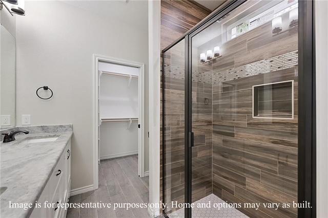 bathroom featuring a walk in closet, a shower stall, double vanity, and a sink