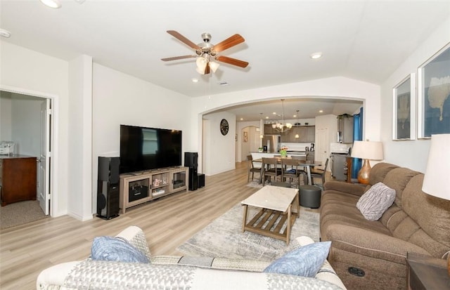 living area with arched walkways, lofted ceiling, light wood-style flooring, recessed lighting, and ceiling fan with notable chandelier