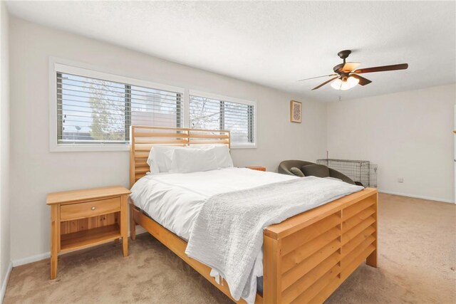 bedroom featuring a ceiling fan, baseboards, and light carpet