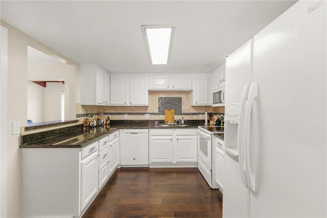 kitchen with dark stone counters, a sink, white cabinets, white appliances, and dark wood finished floors