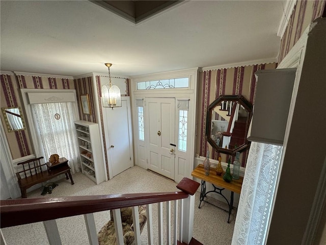 entrance foyer with carpet flooring, ornamental molding, and a chandelier