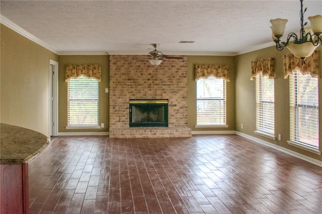 unfurnished living room featuring ornamental molding, a textured ceiling, ceiling fan with notable chandelier, a fireplace, and dark hardwood / wood-style floors