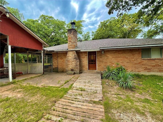 65 Navarro Dr, Hilltop Lakes, TX 77871 - doorway to property featuring brick siding, a chimney, a shingled roof, and a patio