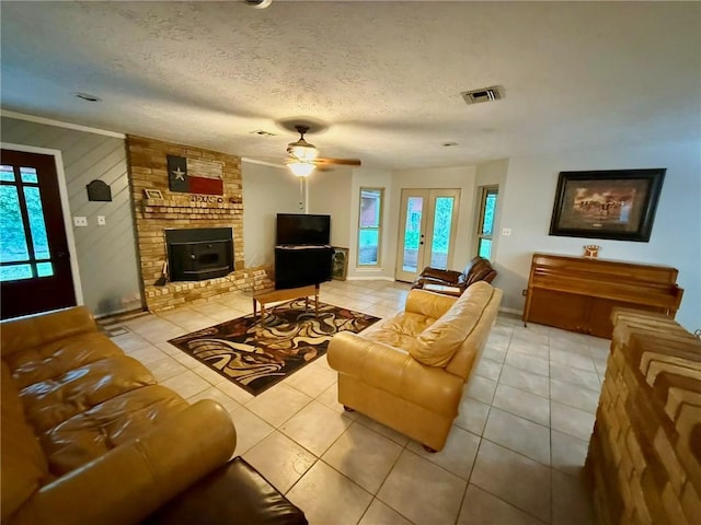 65 Navarro Dr, Hilltop Lakes, TX 77871 - living room with tile patterned floors, a ceiling fan, a wood stove, baseboards, and a textured ceiling