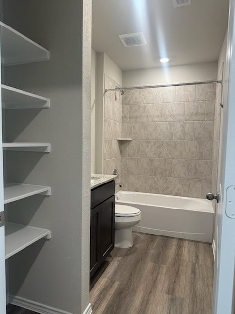 full bathroom with hardwood / wood-style floors, vanity, toilet, and tiled shower / bath