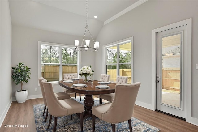 dining space featuring hardwood / wood-style flooring, lofted ceiling, crown molding, and an inviting chandelier