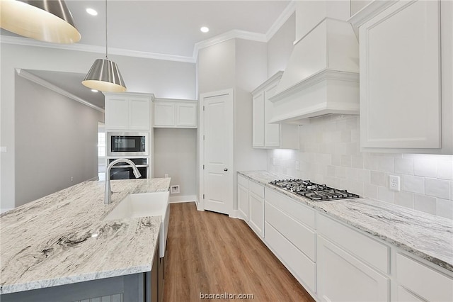 kitchen featuring stainless steel appliances, an island with sink, pendant lighting, white cabinets, and custom exhaust hood