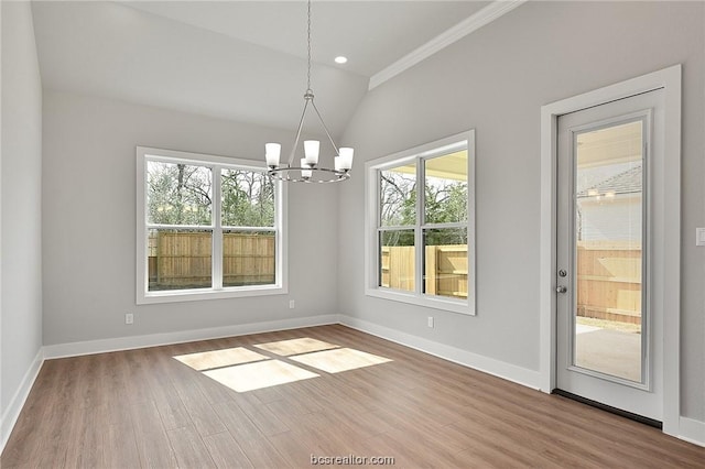 unfurnished dining area with crown molding, hardwood / wood-style floors, a chandelier, and vaulted ceiling