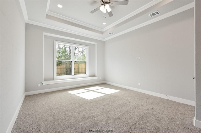 empty room with a tray ceiling, ceiling fan, carpet flooring, and crown molding