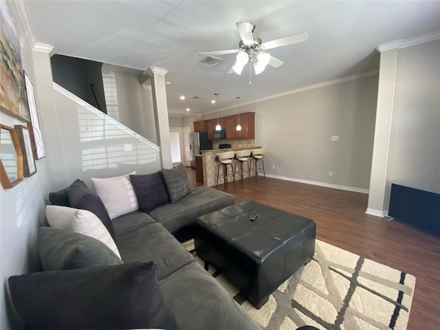 living room with ceiling fan, dark wood-type flooring, ornamental molding, and ornate columns