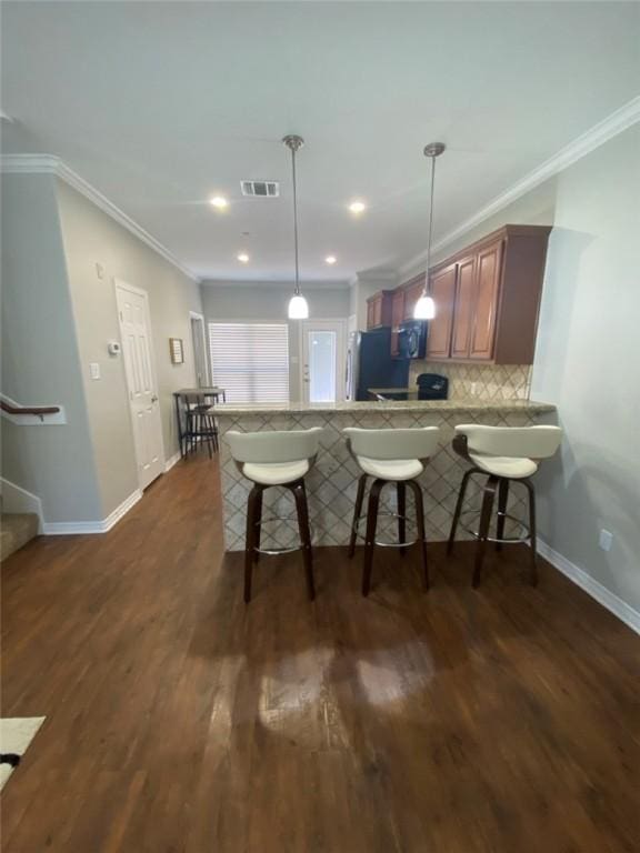 kitchen with fridge, a breakfast bar, kitchen peninsula, pendant lighting, and crown molding