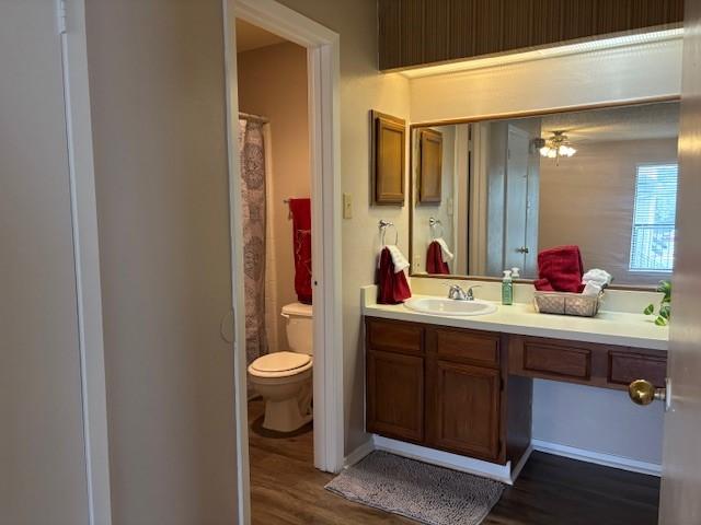 bathroom featuring vanity, curtained shower, wood-type flooring, and toilet