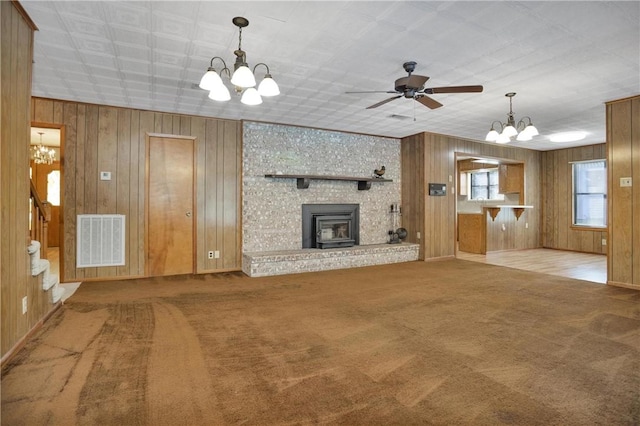 134 Vick Rd, New Waverly, TX 77358 - unfurnished living room with a chandelier, wooden walls, carpet flooring, stairs, and a ceiling fan