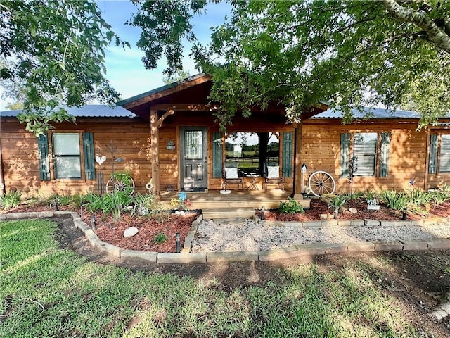 single story home with covered porch and metal roof