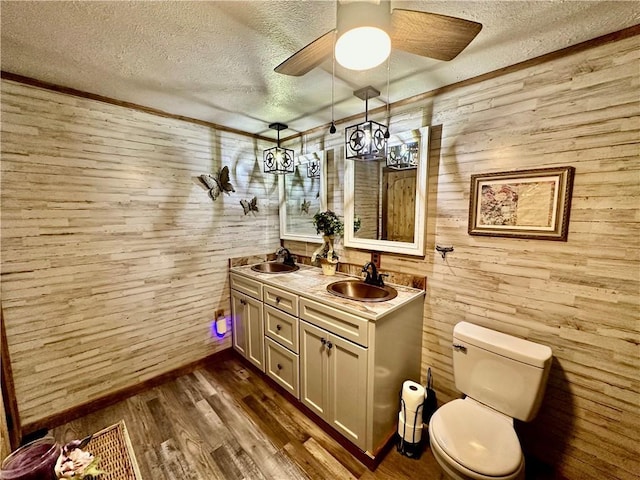 full bath with a sink, wooden walls, and a textured ceiling