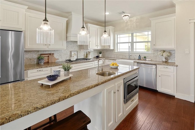 kitchen with stainless steel appliances, white cabinetry, sink, and decorative light fixtures