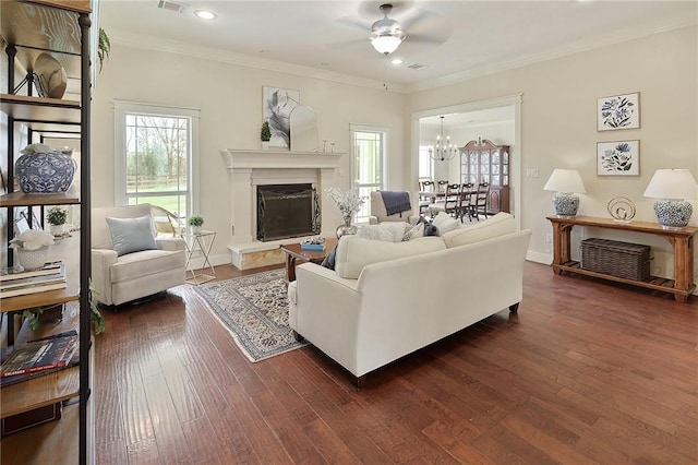 living room with a premium fireplace, crown molding, ceiling fan with notable chandelier, and dark hardwood / wood-style flooring