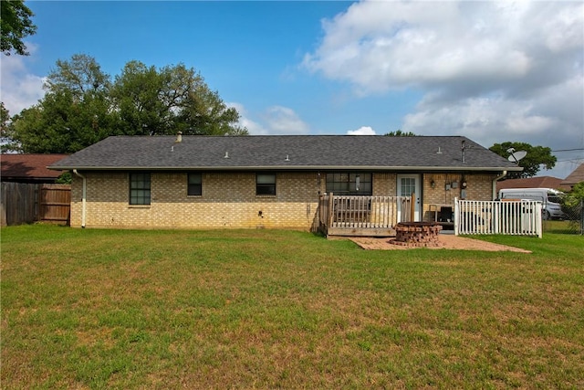 rear view of property with a yard, brick siding, fence, and a shingled roof