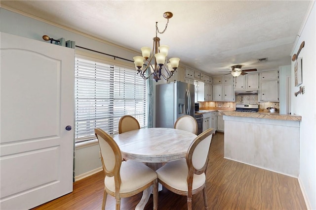 dining space with visible vents, baseboards, dark wood finished floors, and ceiling fan with notable chandelier