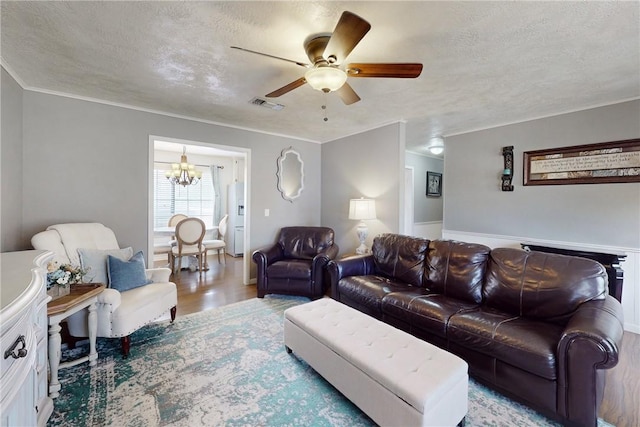 living area with a textured ceiling, visible vents, wood finished floors, and ceiling fan with notable chandelier