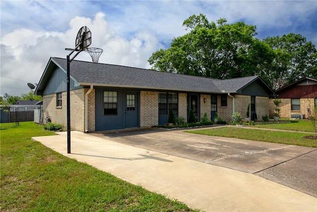 ranch-style house with a front lawn, fence, roof with shingles, brick siding, and driveway