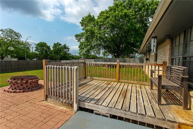 deck featuring a fenced backyard, a yard, and an outdoor fire pit